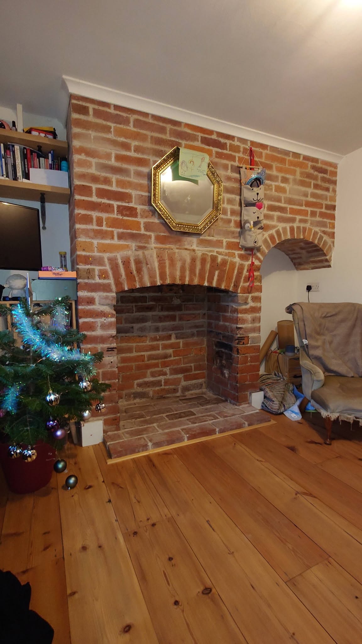 Exposed brick inglenook fireplace in a room with a pine floor