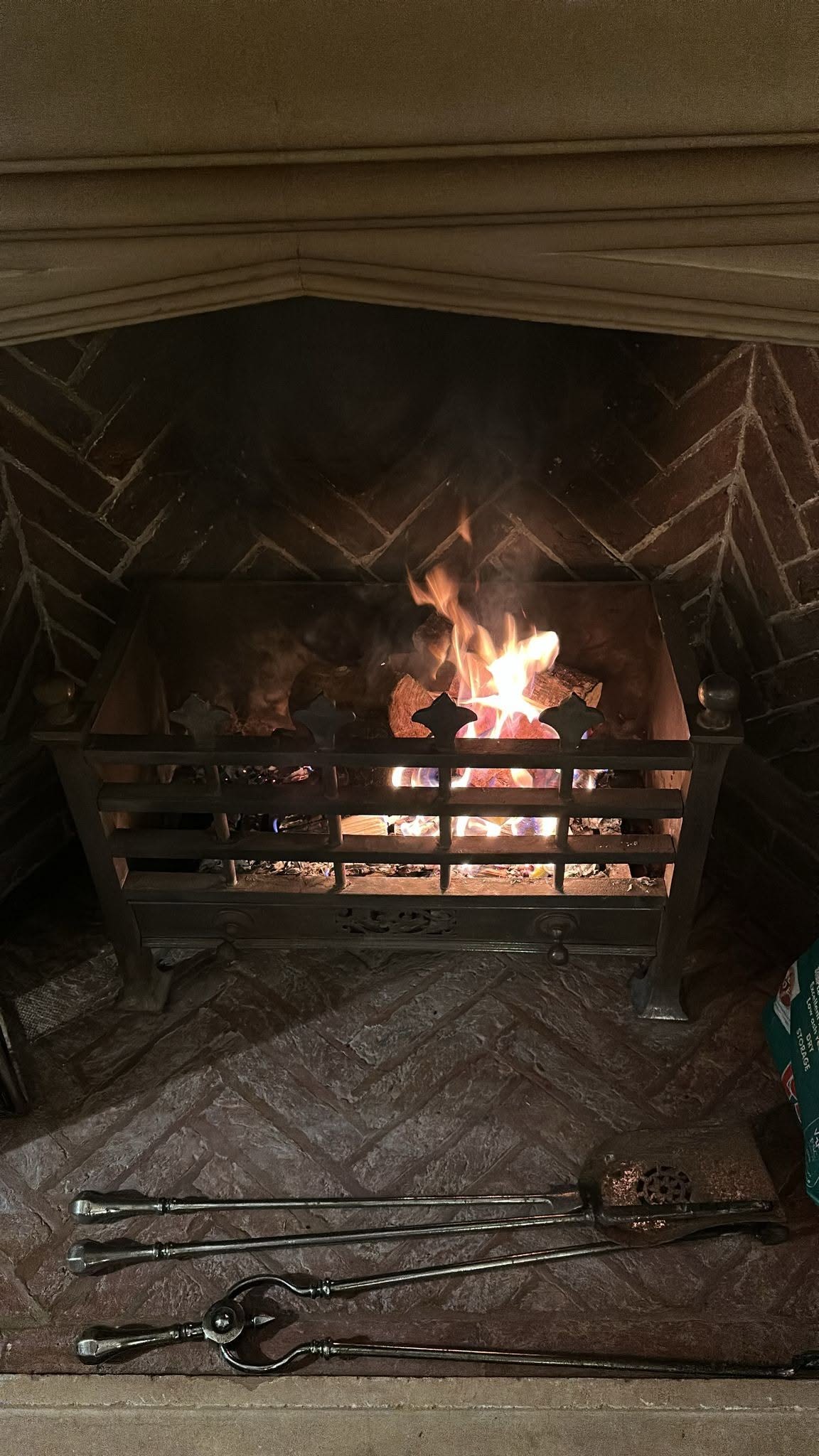 Open fire burning in a cast-iron grate against a herringbone firebrick back