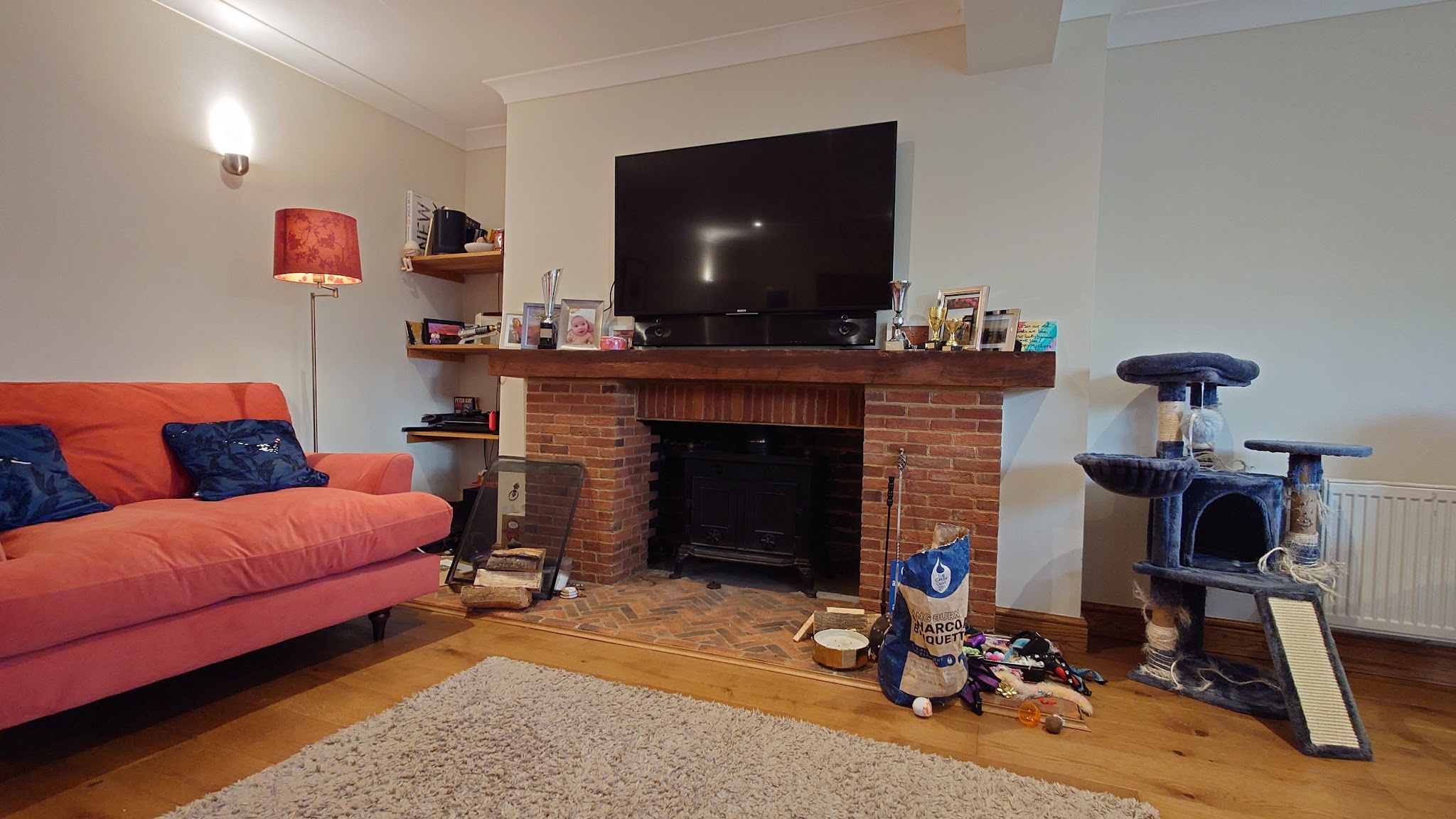 Brick fireplace with a stove insert in a living room with an orange sofa