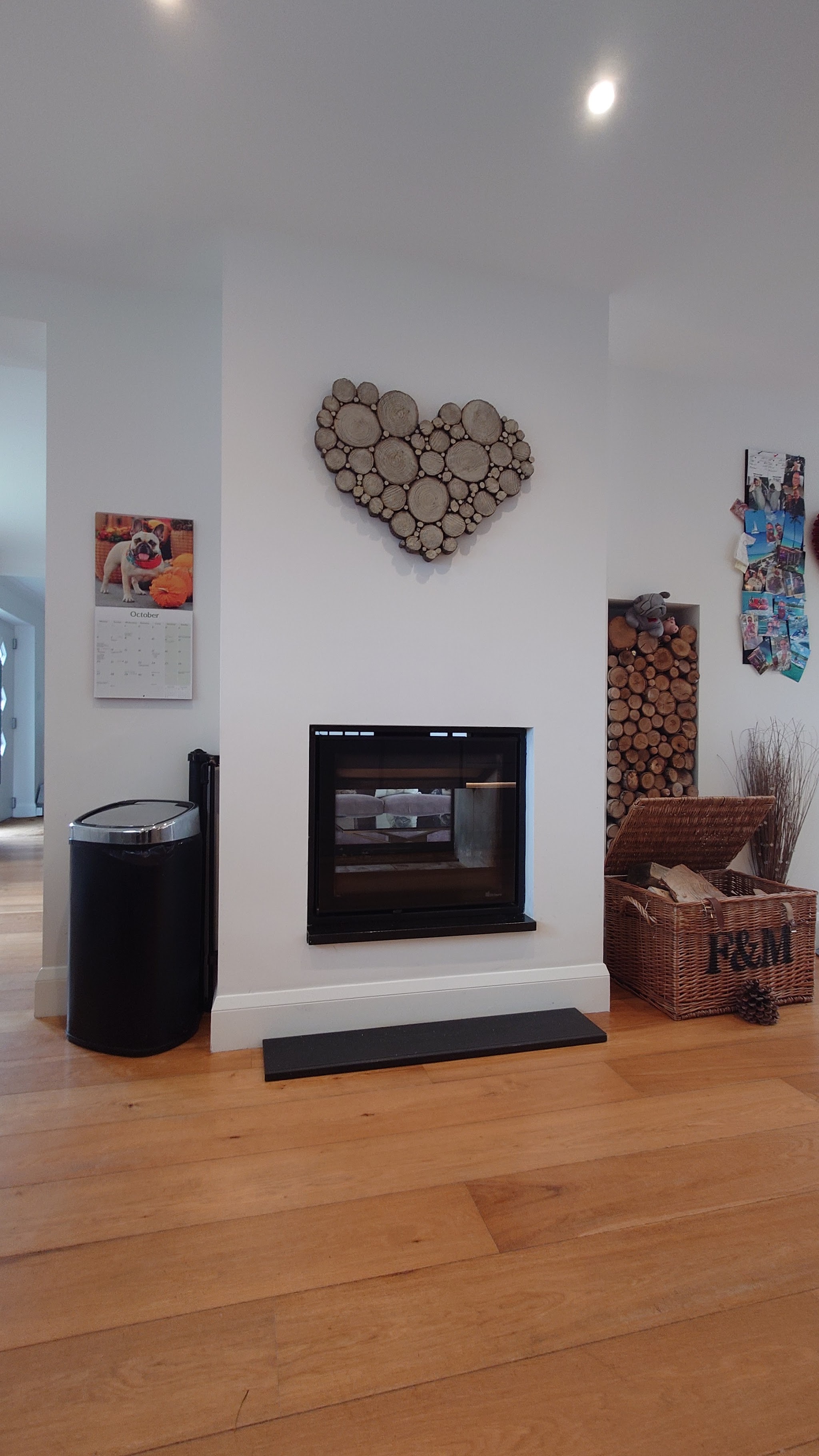 Modern inset fire in a white chimney breast with a log store beside it