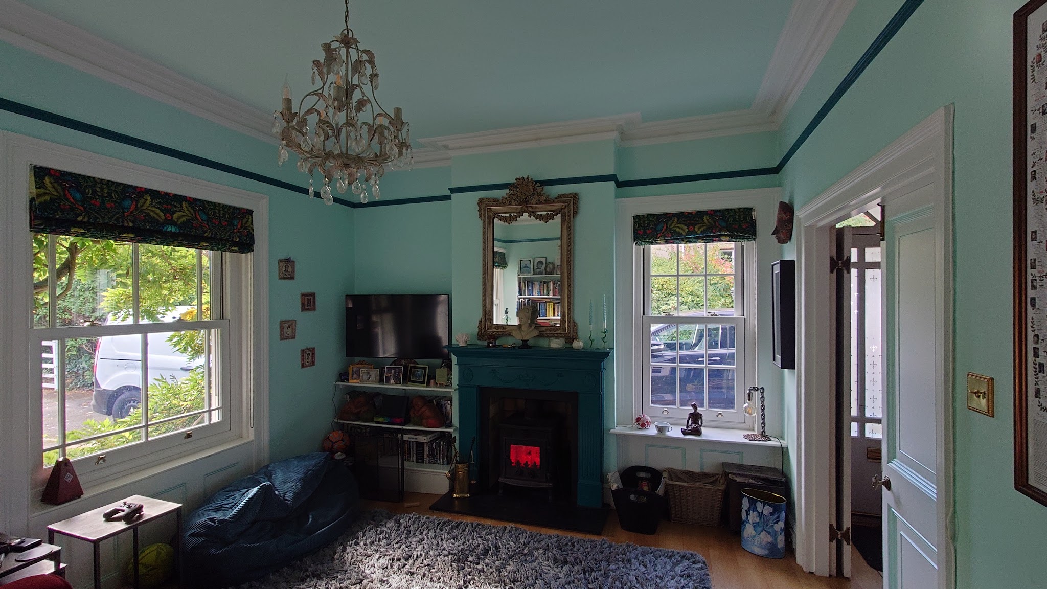 Mint-green period room with a lit stove in a dark green surround