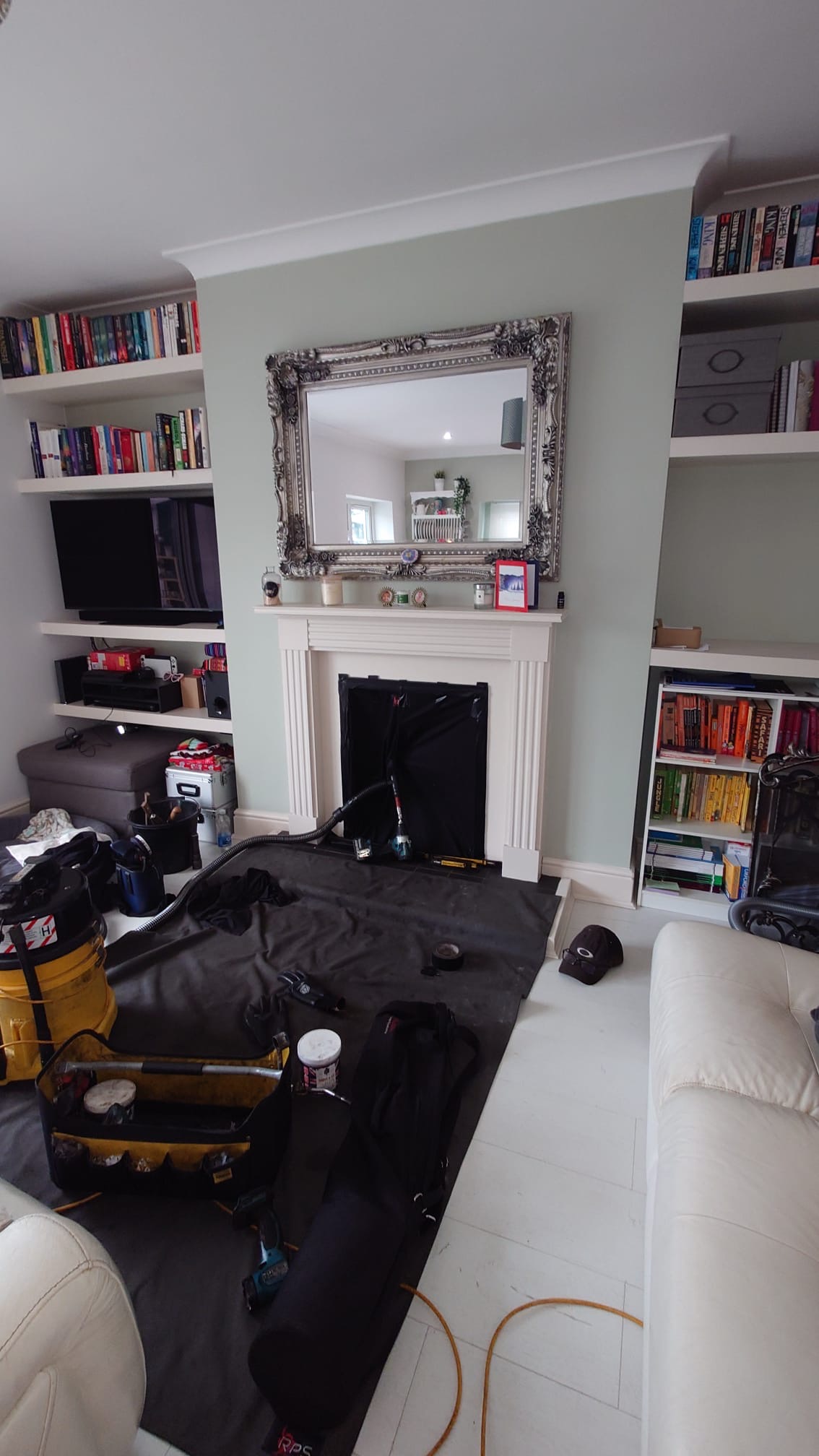 Dust sheets, a vacuum and sweeping rods laid out in front of a white fireplace during a sweep